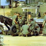 One of the gun crews B 2/17th, Chief of Firing Battery (Smoke) sitting on chair, Lt. Bessie. Btn HQs was in the white colonial building at the top of picture.